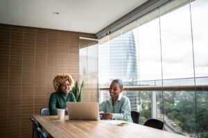 two women working on laptops in an office